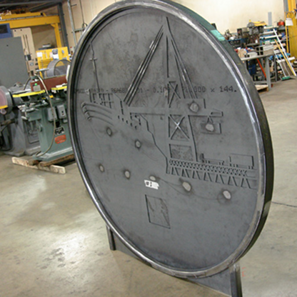 Round metal sign featuring embossed artwork of a ship, oil rig, and industrial structures with a solid metal finish.