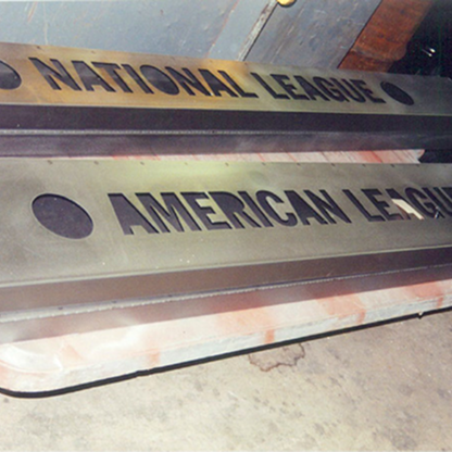 Metal signs with engraved text 'NATIONAL LEAGUE' and 'AMERICAN LEAGUE' displayed on a workshop floor